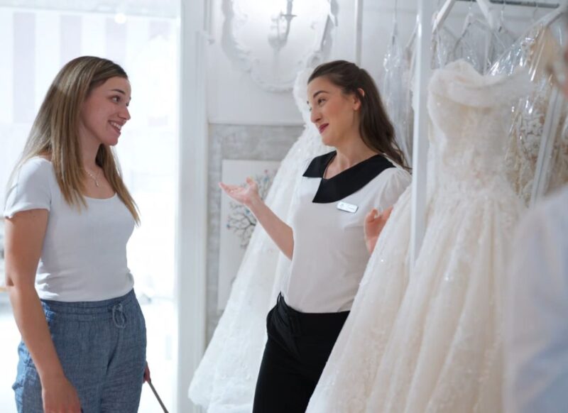 devojka u salonu priča ca drugom devojkom koja radi tu i gledaju venčanicu